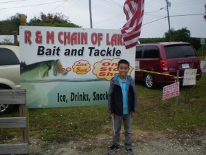 Boy standing in front of R & M Chain of Lakes Bait and Tackle